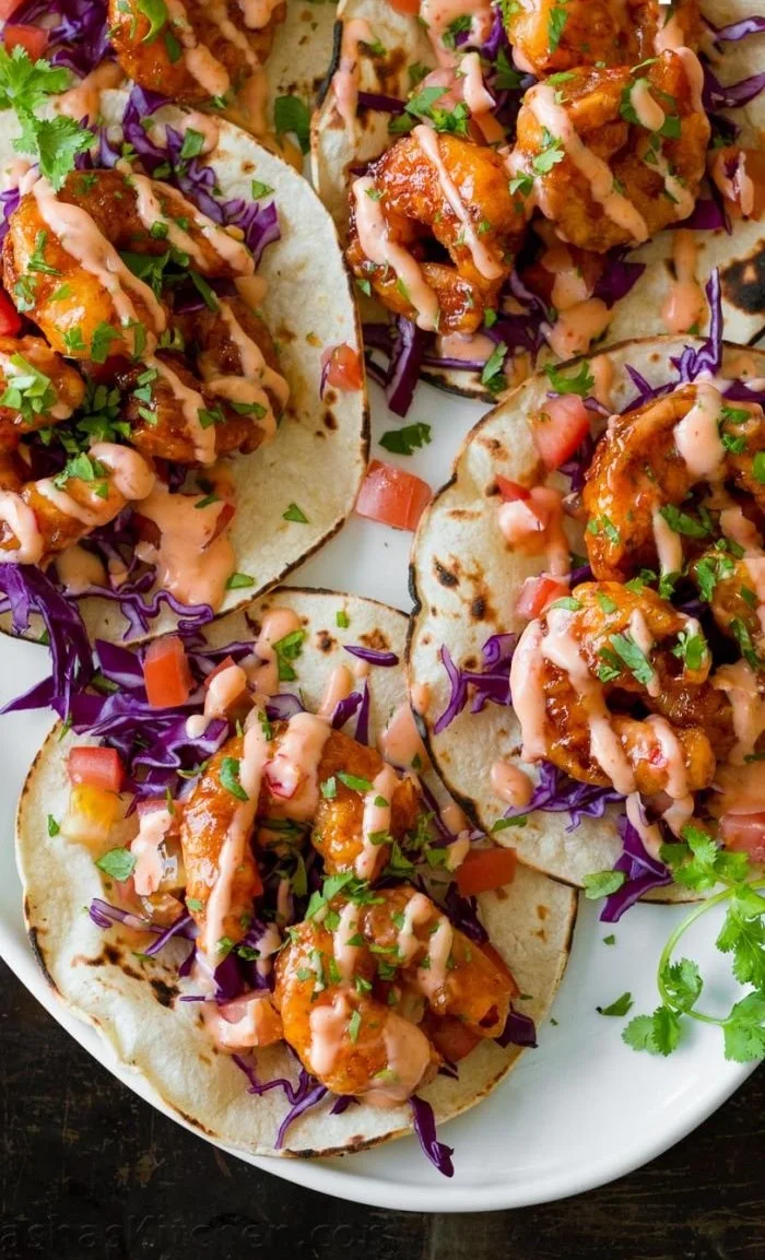 Delectable Bang Bang Shrimp Tacos served with fresh ingredients and a spicy sauce.