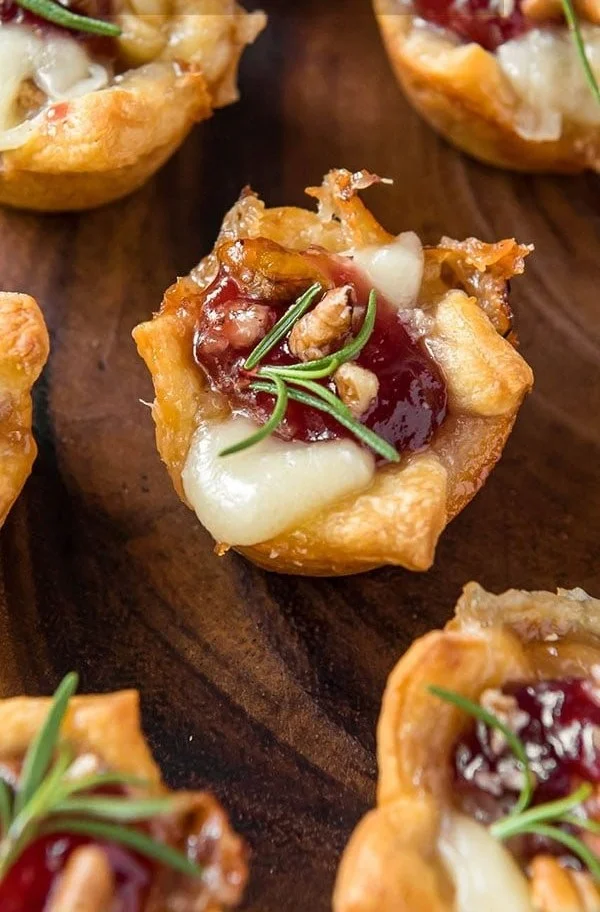 Cranberry Brie Bites served on a platter, garnished with herbs.