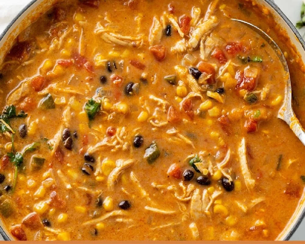 Bowl of creamy chicken tortilla soup topped with tortilla chips and avocado.