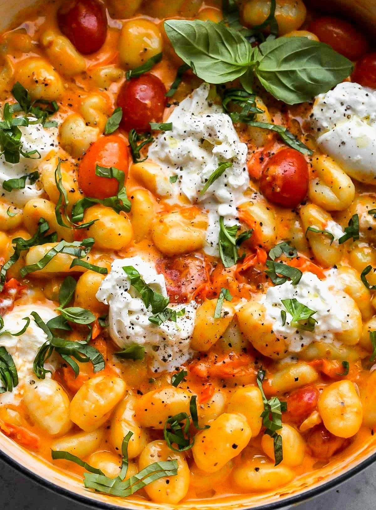 Creamy tomato gnocchi with burrata served in a bowl, garnished with herbs