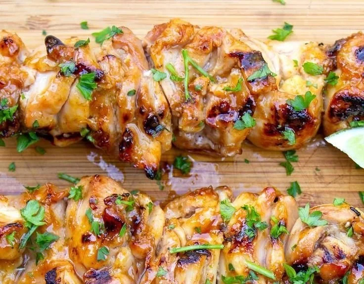Spicy honey-lime chicken garnished with fresh herbs, served on a plate.