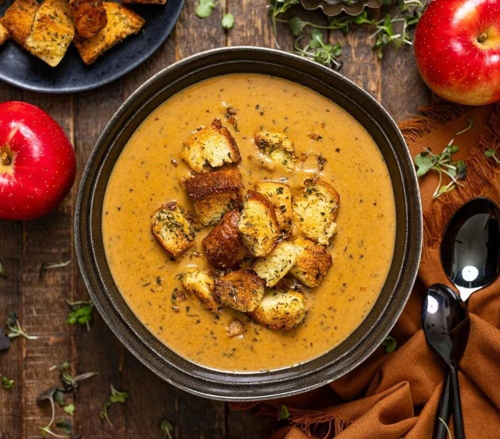Delicious creamy roasted apple pumpkin soup in a bowl garnished with herbs