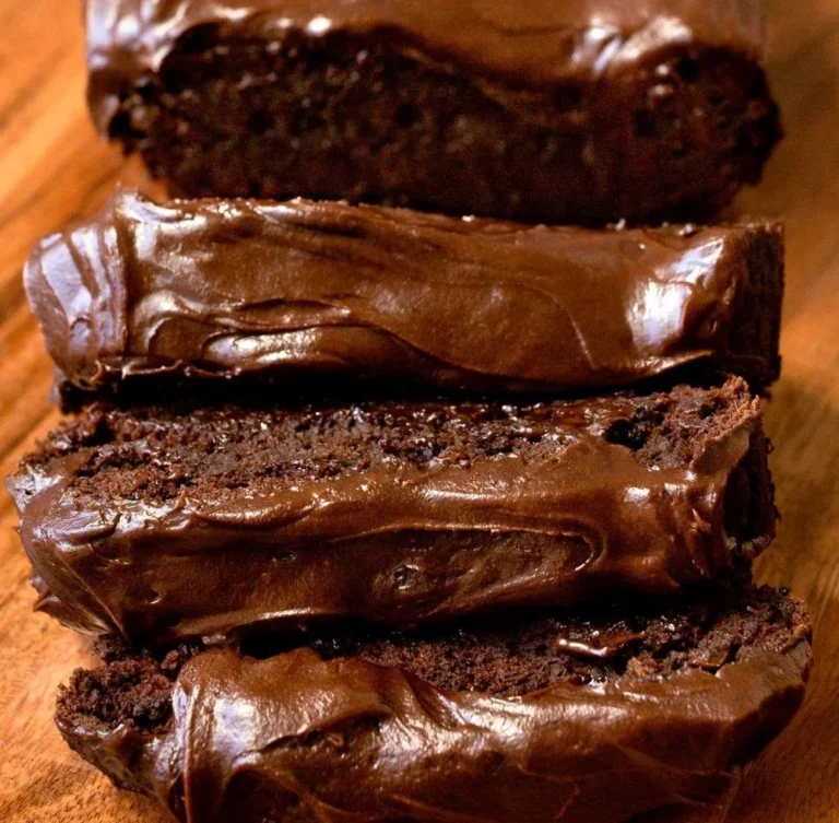 Slices of dark chocolate pumpkin bread with creamy frosting on a rustic background