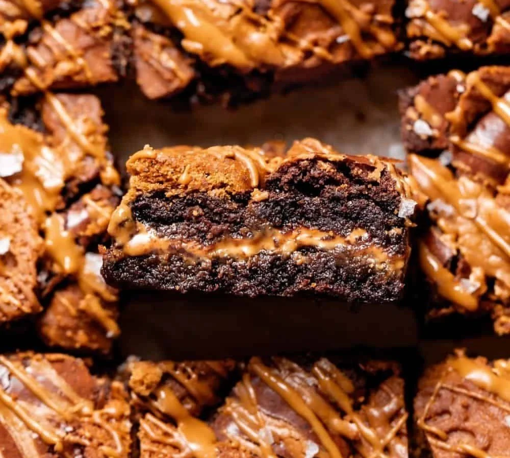 Delicious Biscoff brownies served on a white plate with chocolate drizzle.
