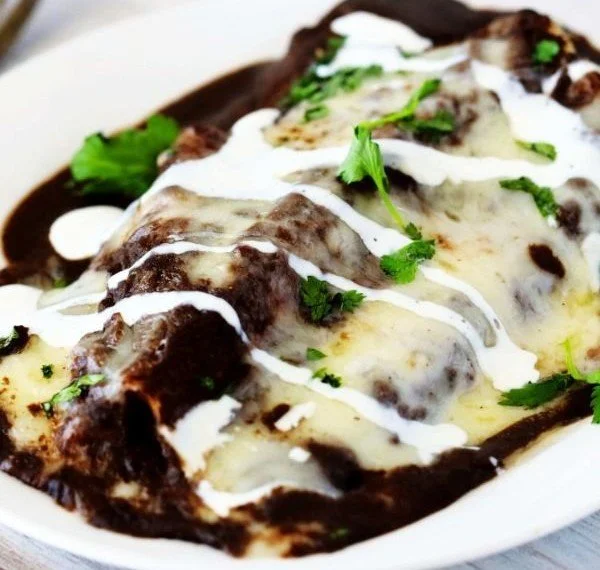 Delicious enfrijoladas topped with black bean sauce, ready to be served.