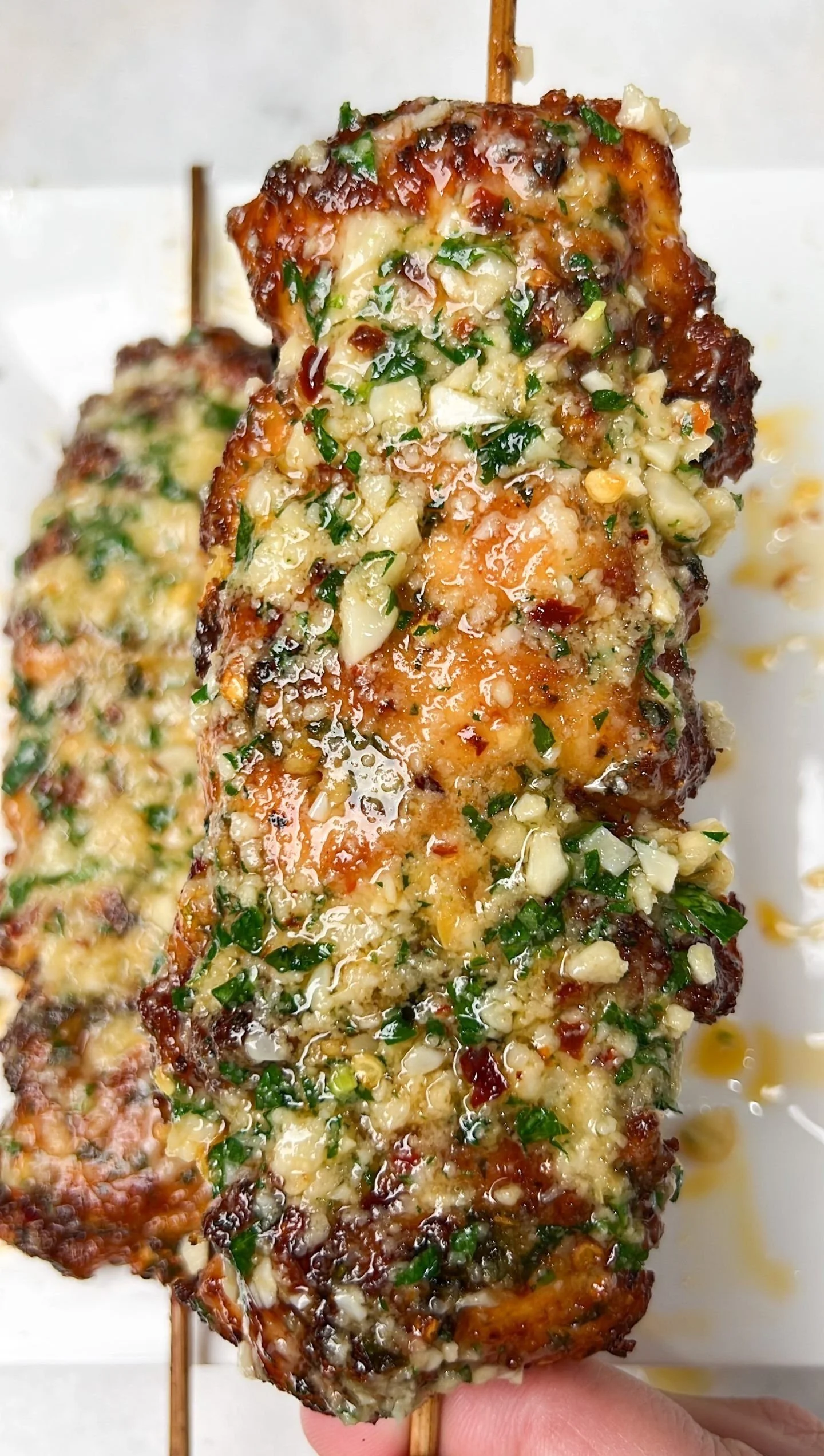 Garlic Parmesan Chicken Skewers on a grill with fresh herbs