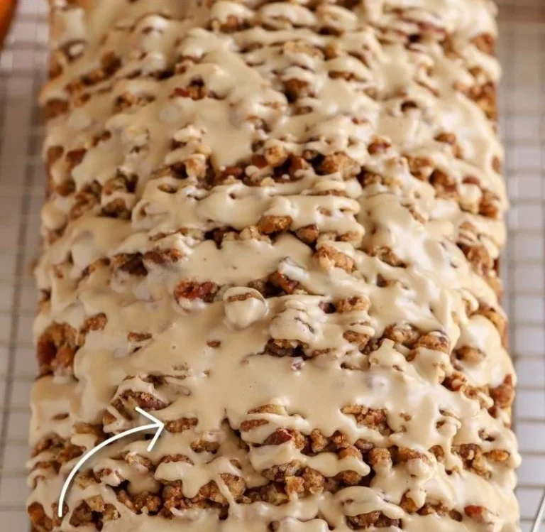 Slice of moist maple pumpkin bread on a wooden table, garnished with walnuts.