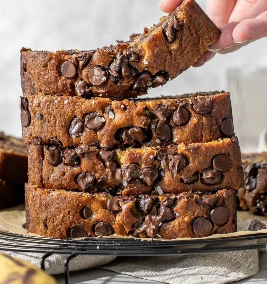 Moist chocolate chip banana bread slices on a wooden cutting board