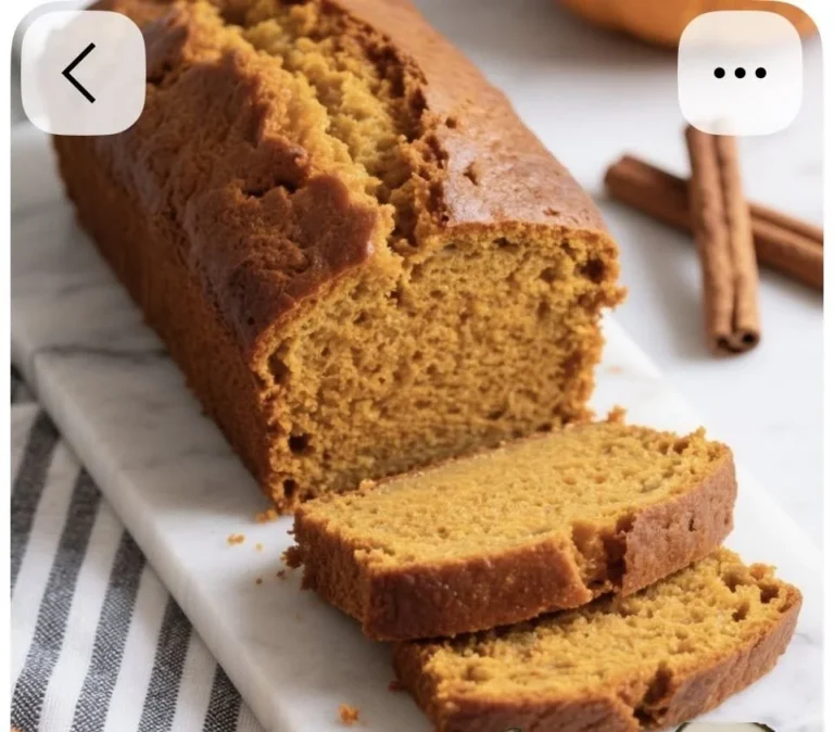 Sliced nut-free pumpkin bread on a wooden table with autumn decorations.