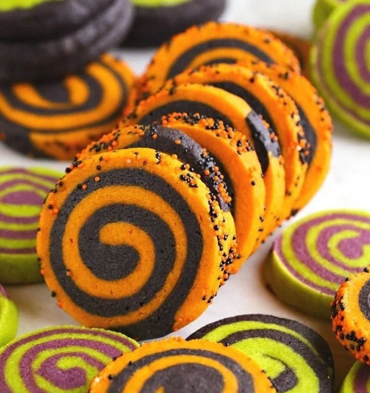 Pinwheel sugar cookies decorated for Halloween with colorful swirls and spooky designs.