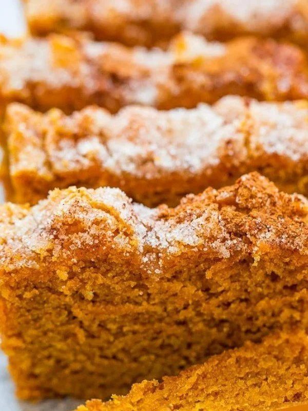 Delicious pumpkin bread topped with cinnamon sugar on a rustic wooden table