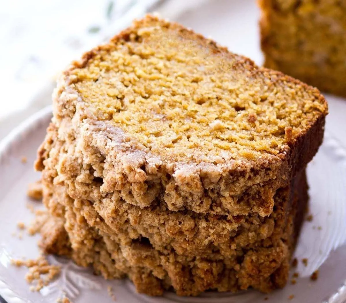 Slice of pumpkin bread with crumb topping on a wooden board