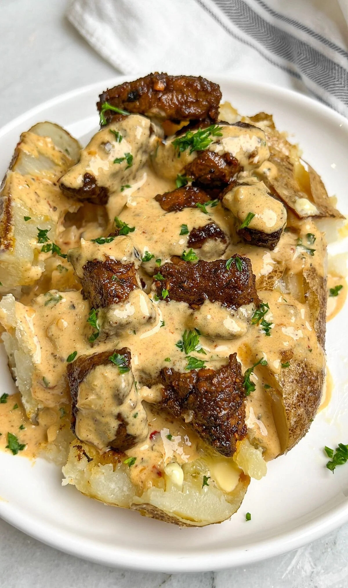 Steak bites served on a loaded baked potato with toppings