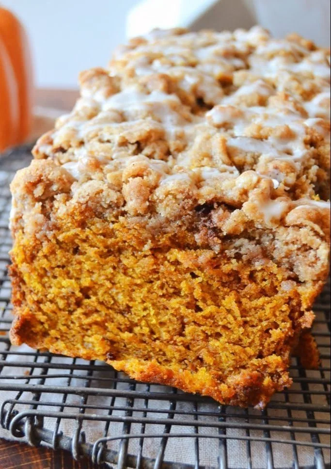 Streusel-topped pumpkin apple bread loaf on a wooden table