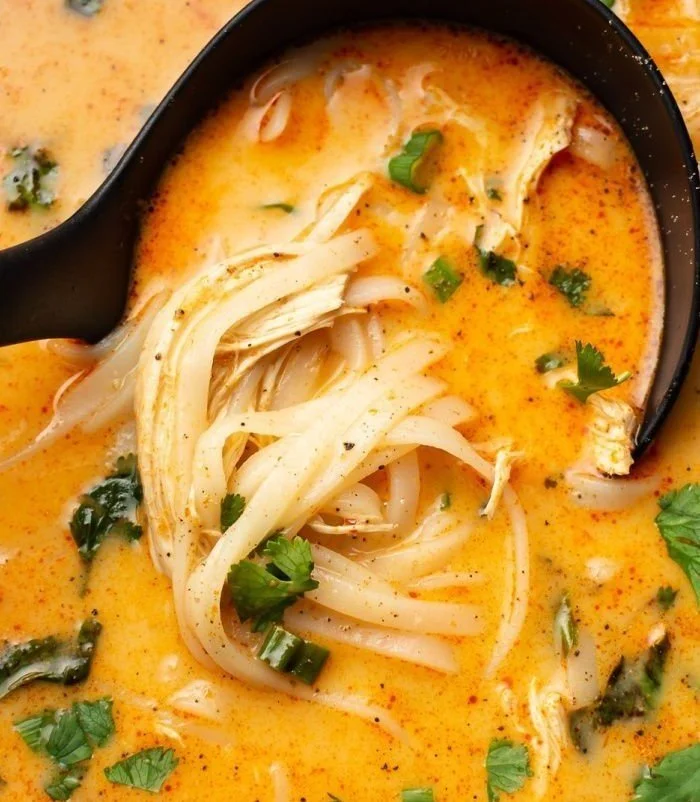 Bowl of flavorful Thai Chicken Soup garnished with herbs and lime